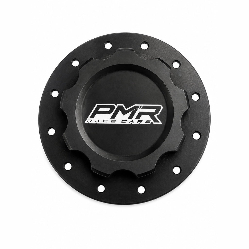 A black anodized aluminum fuel cell cap with a white and black PMR logo in the center and pre-drilled bolt holes around the outer rim, shown on a white background.